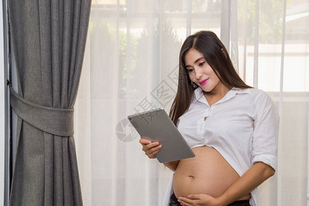 怀孕妇女在家中玩手机游戏而她却在家庭图片