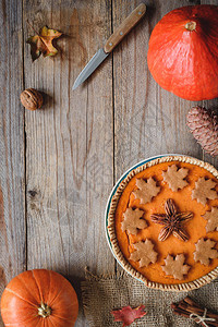 南瓜馅饼南瓜刀和木制老桌子上的红叶复制文本空间秋季舒适食品感恩背景图片