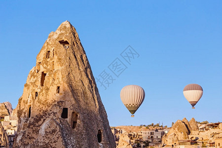 热气球飞越日落时土耳其主要旅游景点之一卡帕多西亚洞穴镇和岩石图片