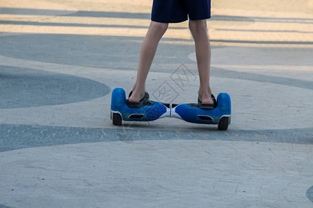 在城市街道上骑着自平衡迷你气垫板的男孩的腿户外电子滑板车个人便携式生态交通工具陀螺滑板车hyroscooter智能平衡轮背景图片
