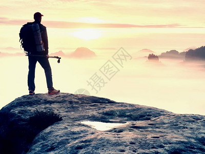 手持带杆子的木轮阳光春夏和导游留在山尖悬崖上在迷雾谷上空的岩石观察点背景图片