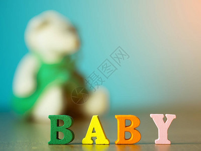婴儿由木字母颜色制成的英文字母木桌上的字母婴儿和小熊和背图片