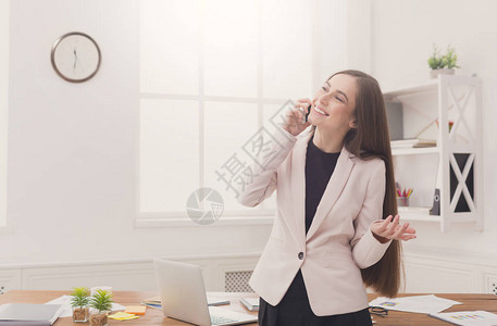 微笑的女商人在办公室工作场所通过电话交谈图片