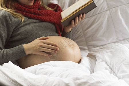 正在看书的孕妇手放在肚子上图片