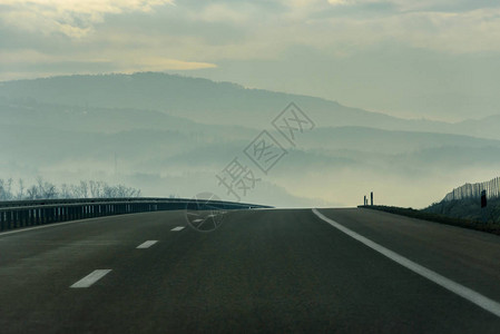 通向山坡的沿风公路上的雾穿过农村地图片