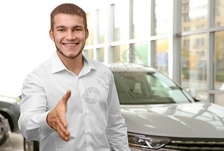 英俊的汽车销售员在经销中心为握图片