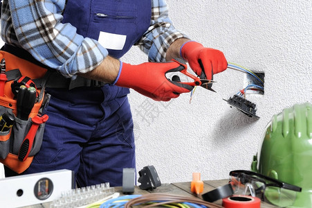 手有套和隔热工具保护的电工在住宅电气装置中遵守安全条例图片