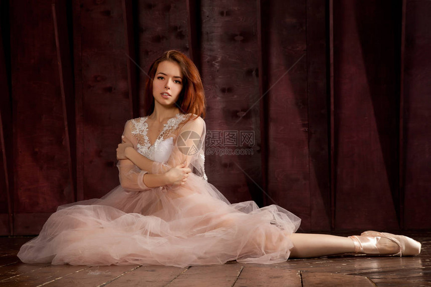 一个美丽的欧洲年轻女孩坐在地板上穿着平淡粉红彩色芭蕾舞女装和图片