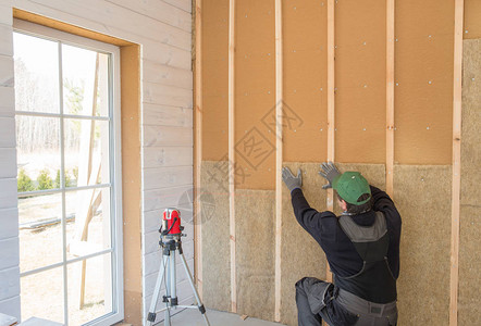 工人用一层木板完成墙面的抛光工作使用激光线水平用木纤维板材建筑隔热生态木框架房屋背景图片