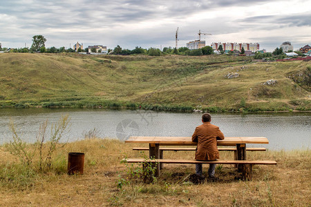 男人坐在桌边的河岸上看着远处的城市图片