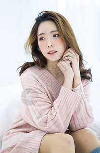 年轻的亚洲美女穿着暖和的针织衣服在家里粉红色模特时装拍摄秋天冬天季节图片