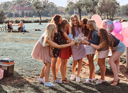 一群女朋友一起在户外公园庆祝生日的乐趣快乐的朋友欢呼与果汁在野餐派对户外背景图片
