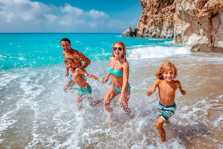 母亲与父亲和孩子在夏天海滩奔跑图片