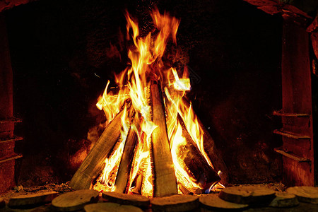 在壁炉的黑暗背景上燃烧木柴背景图片