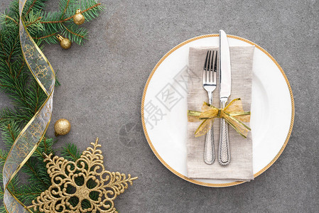 在圣诞球和金星装饰的常青树枝附近用金丝带包裹着叉子和刀子的高架视野图片