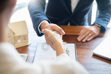 房屋开发商代理人或财务顾问和客户在签署文件后握手作为与公司的成功协议合同背景图片