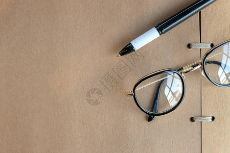 将旧眼镜和笔放在桌上的开放书上图片