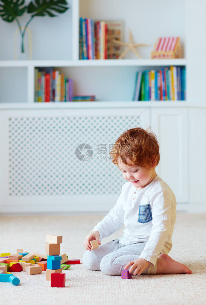 可爱的蹒跚学步的小男孩玩木块建高塔图片