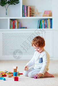 可爱的蹒跚学步的小男孩玩木块建高塔背景图片