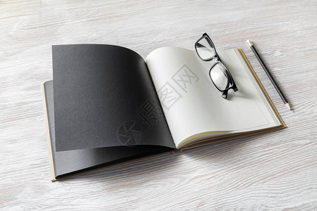 木桌背景上的空白书眼镜和铅笔反图片
