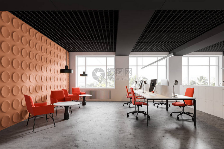 现代开放空间办公室的内部设有明亮的橙色几何图案墙壁带橙色椅子的大型白色电脑桌以及带扶手椅和咖啡桌的休息区图片