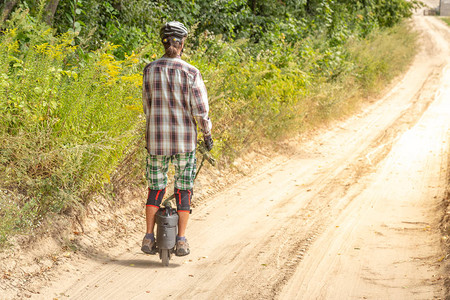男人在乡间小路上学习骑单轮车背景图片