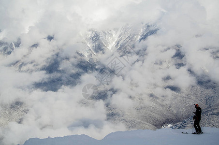 一个滑雪者站在云层的边缘背景图片