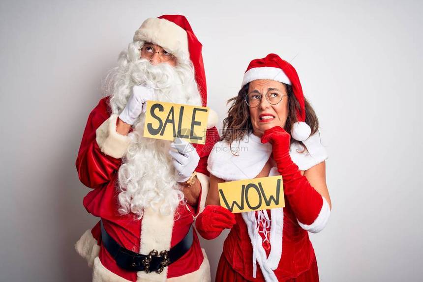 一对穿着圣诞老人服装的夫妇在孤立的白色背景上举着哇和销售横幅图片