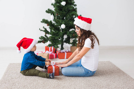 圣诞节单亲家庭和假日概念可爱的小男孩拿着圣诞礼物给他的母亲在家图片