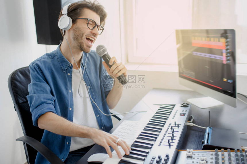 男人对着麦克风唱歌在录音室做混音器在广播演播室做DJ音乐制作人正在录音室的合成器和电脑上作曲图片