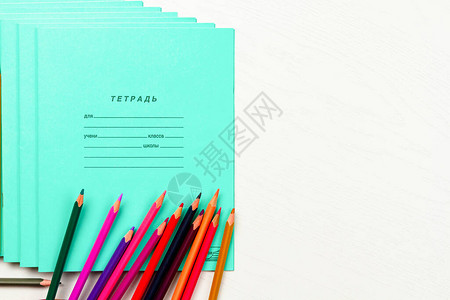 彩色铅笔和学校笔记本放在白色木桌刻字笔记本上图片