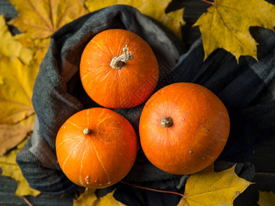 感恩节背景橙色南瓜和深色木质背景上的秋叶图片