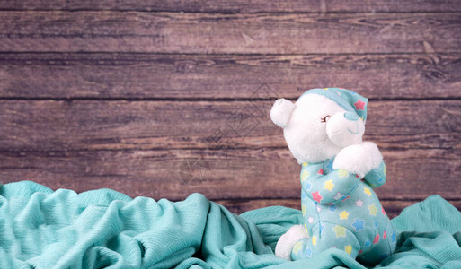 可爱的白色泰迪熊在蓝色织物背景上祈祷新生儿圣餐确认或洗礼贺图片