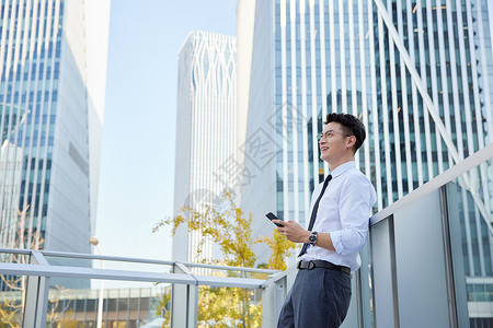 户外玩手机的商务男士形象商务楼高清图片素材