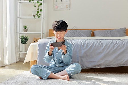 儿童睡衣假日在家玩手机的小男孩背景