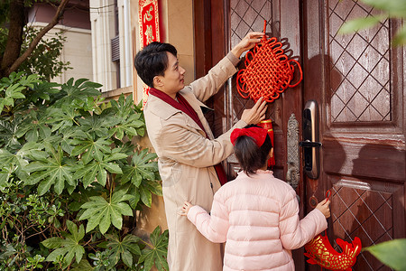 新春开门口爸爸和女儿在门口装饰中国结背景