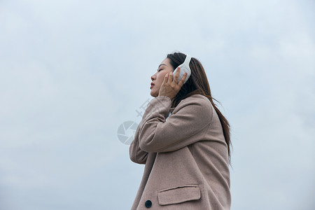 年轻女性在江边带着耳机伤感情绪背景