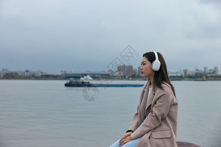 青年女性在江边带着耳机伤感情绪背景