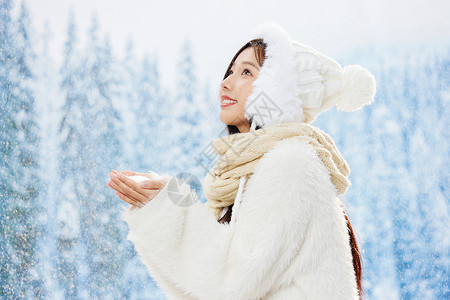 雪地里捧雪花的青年女性高清图片