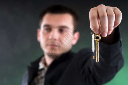 年轻商人手里握着钥匙黑背景图片