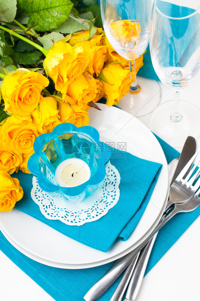 配有黄色玫瑰眼镜蜡烛餐巾和蓝色和黄色图片
