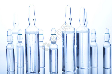 白色和蓝色背景上带有液体的玻璃药用安瓿瓶图片