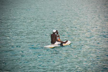 年轻的塞舌尔男子在海中冲浪板上卖水果背景图片