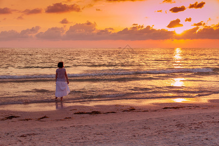 女人享受海洋上美丽的日落图片