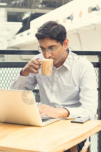 亚裔印度商人在喝杯热牛奶茶时使图片