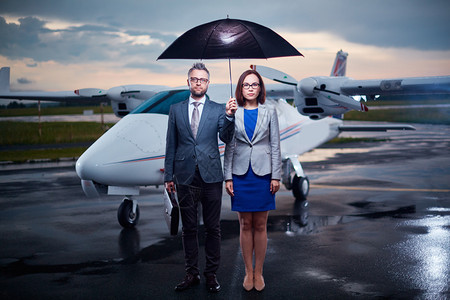 认真的商业伙伴在伞式保护下观看机场雨夜的摄背景图片