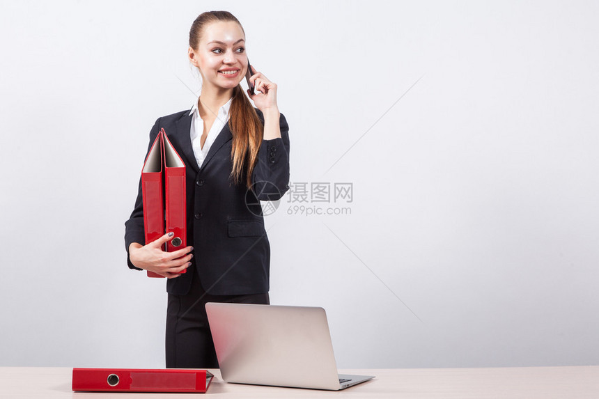 年轻女孩经理站在一张白背景的桌子旁边图片