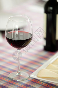 一杯红葡萄酒和芝士餐盘桌子图片