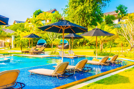 在酒店度假胜地的豪华户外游泳池周围保护伞和椅子背景图片