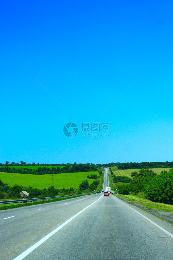 柏油路边有绿色的田野蓝天图片